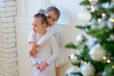 İki genç bale dansçısı sarılmak Noel ağacı yakınındaki