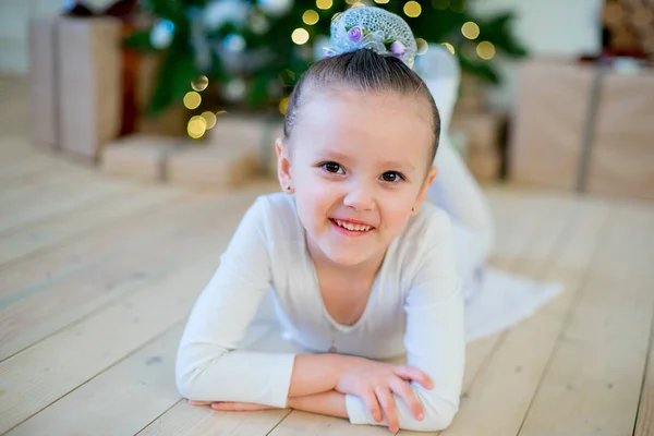 Joven bailarina de ballet tendida cerca del árbol de Navidad —  Fotos de Stock