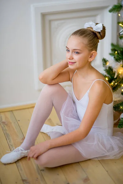 Junge Balletttänzerin sitzt am Weihnachtsbaum — Stockfoto