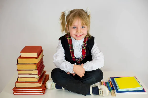 Молодая школьница в форме сидит на столе — стоковое фото