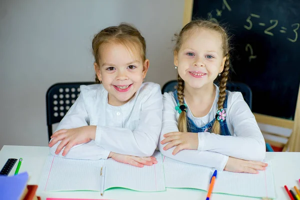 Porträt zweier junger Schulmädchen am Tisch — Stockfoto