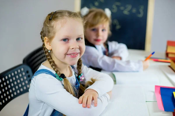 Porträtt av två unga skolflickor som sitter vid bordet — Stockfoto