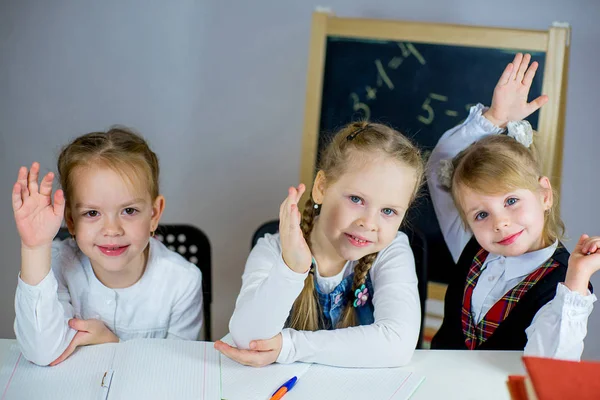 Tres jóvenes colegialas sentadas a la mesa — Foto de Stock