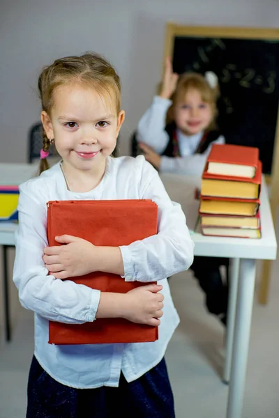 Zwei junge Schulmädchen mit roten Schulbüchern — Stockfoto