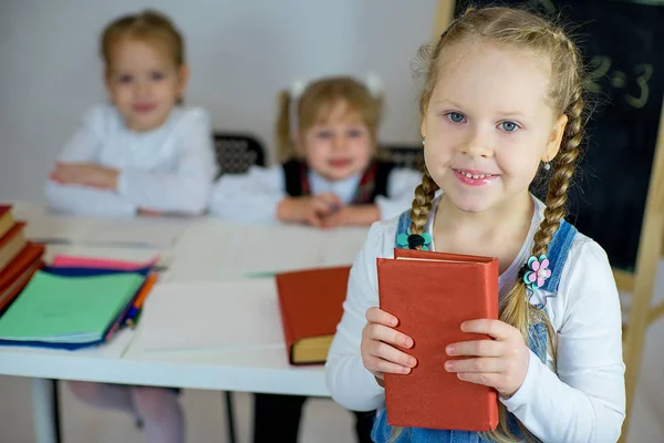 Tres colegialas jóvenes con libros de texto rojos — Foto de Stock