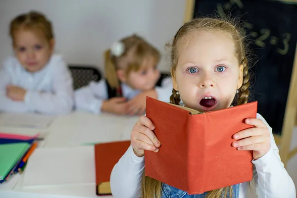 Tres colegialas jóvenes con libros de texto rojos — Foto de Stock