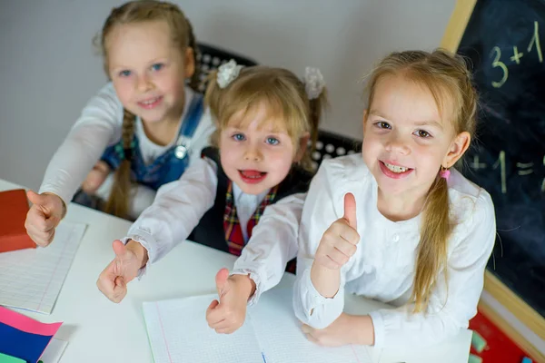 Drei junge Schulmädchen sitzen am Tisch — Stockfoto