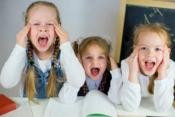 Tres jóvenes colegialas sentadas a la mesa — Foto de Stock