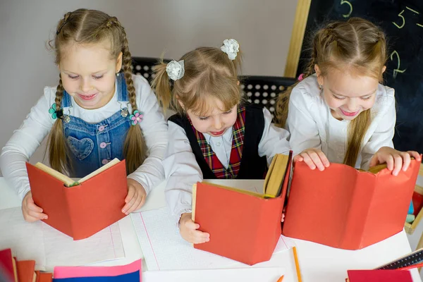 Три школьницы с красными учебниками — стоковое фото