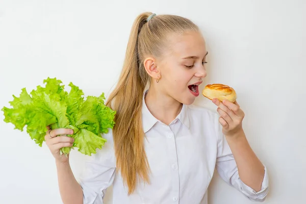 Młoda dziewczyna wybiera między sałata i pieczenia na białym tle — Zdjęcie stockowe