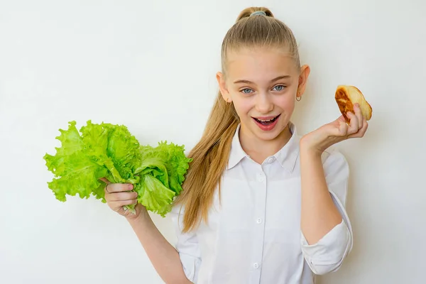 Junges Mädchen hat die Wahl zwischen Salat und Backen — Stockfoto