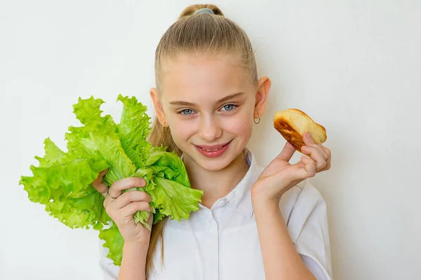 Junges Mädchen hat die Wahl zwischen Salat und Backen — Stockfoto