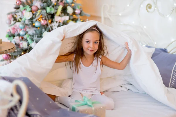 Niña despierta en su cama en la mañana de Navidad — Foto de Stock