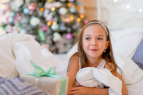 Niña despierta en su cama en la mañana de Navidad — Foto de Stock