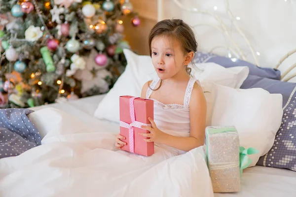 Niña despierta en su cama en la mañana de Navidad — Foto de Stock