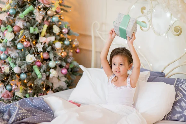 Niña despierta en su cama en la mañana de Navidad — Foto de Stock