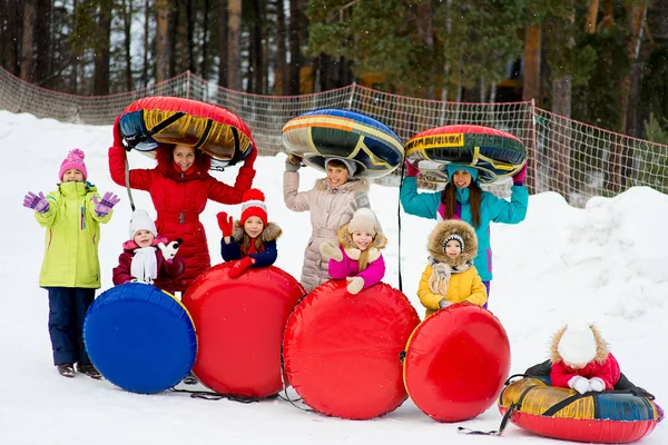 Kinderen op de buizen van de sneeuw afdaling op de winterdag — Stockfoto