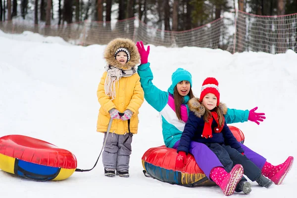 Kinderen op de buizen van de sneeuw afdaling op de winterdag — Stockfoto