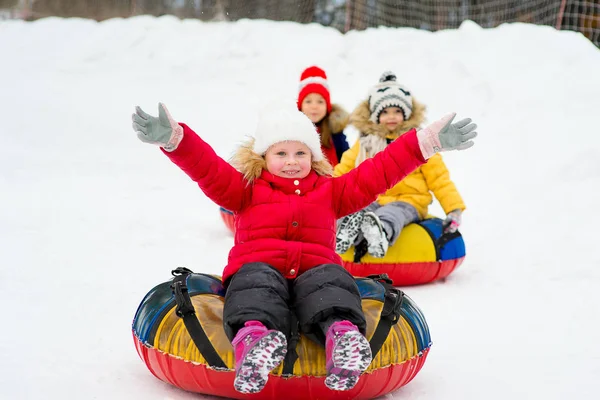 Kinderen op de buizen van de sneeuw afdaling op de winterdag — Stockfoto