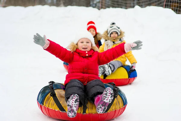 Bambini sui tubi di neve in discesa durante la giornata invernale — Foto Stock