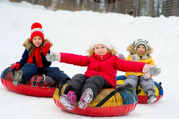 Kinderen op de buizen van de sneeuw afdaling op de winterdag — Stockfoto