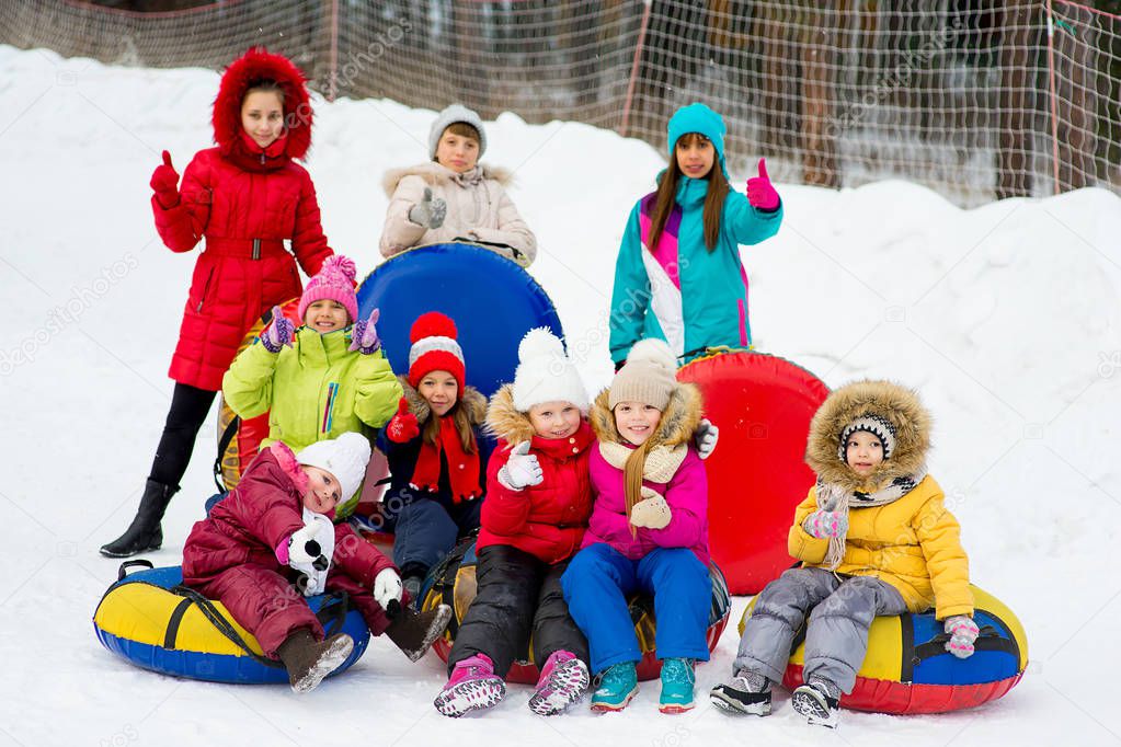 Kids on snow tubes downhill at winter day
