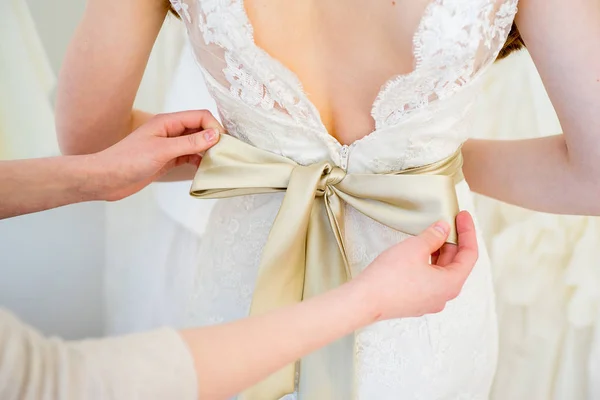 Подружка невесты обвязывает бант на свадебном платье — стоковое фото