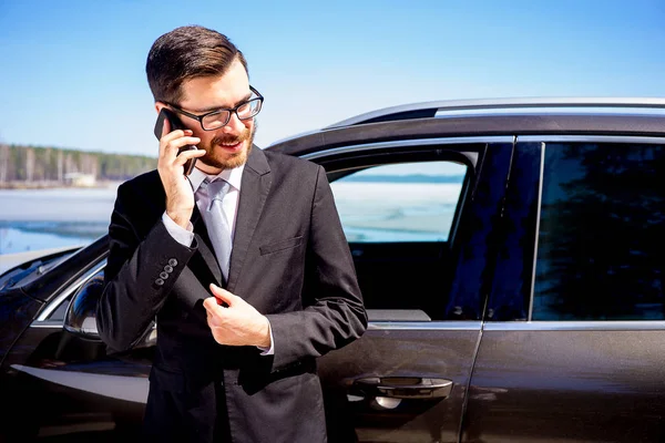 Empresário em um celular perto de seu carro — Fotografia de Stock