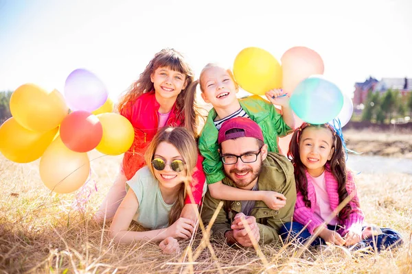 Familia acostada sobre hierba con globos — Foto de Stock