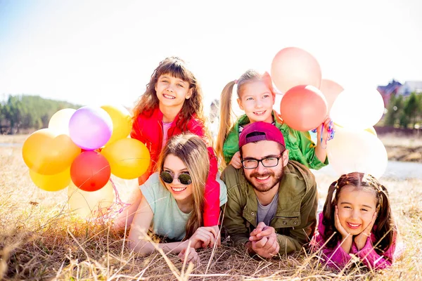 Aile balonlarla çim üzerinde yalan