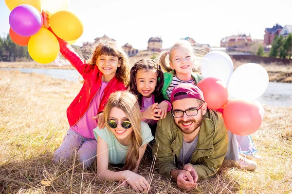 Aile balonlarla çim üzerinde yalan