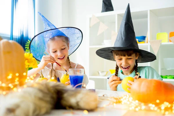 Two girls painting pumpkins