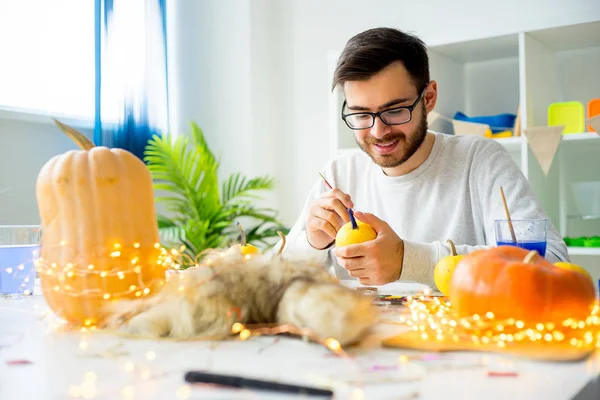 Guy painting pumpkins