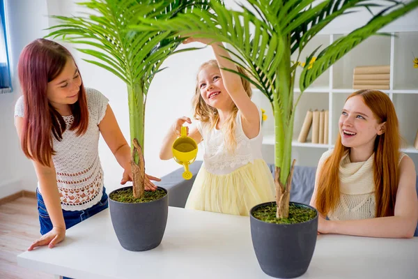 Mor vatten blommorna med sina söta döttrar — Stockfoto