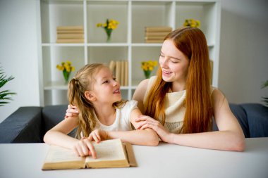 Anne ve kızı kitap okuyor.