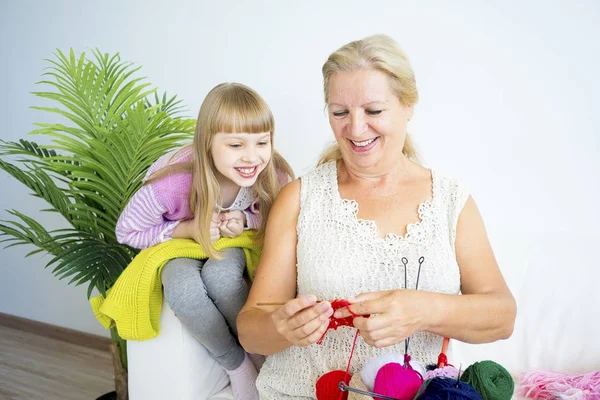 Grandmother knitting with granddaughter