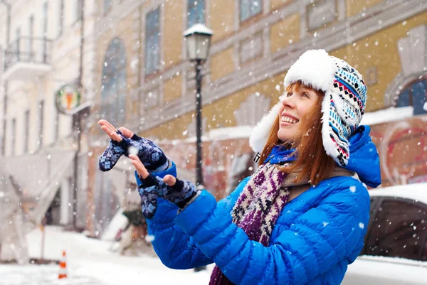 Menina elegante jovem se alegra primeira neve. Neve na cidade. Deixa nevar. Menina pegar a neve com as mãos . — Fotografia de Stock