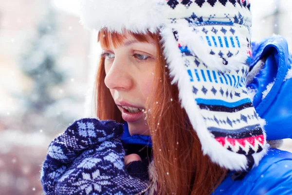 年轻的红头发的女孩在雪中。女孩温暖呼吸的手. — 图库照片