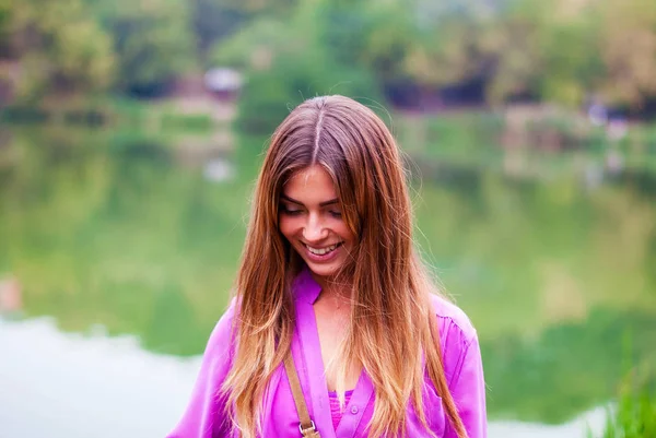 Молодая красивая девушка улыбается в парке. Фиолетовая блузка . — стоковое фото
