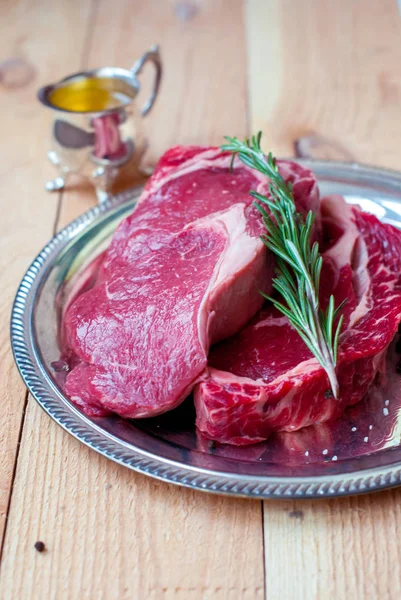 Dua steak daging iga mentah dengan rosemary dan minyak zaitun . — Stok Foto