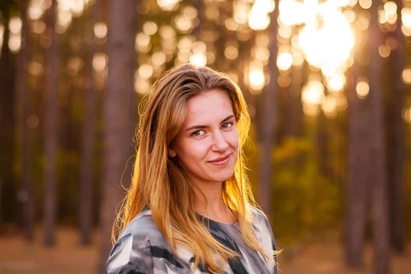 Ensam flicka leende vid solnedgången i skogen. — Stockfoto