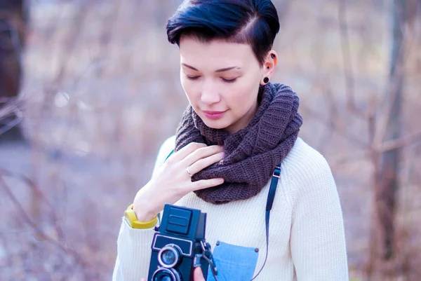 Hermosa chica reflexiva con una cámara vintage y pelo negro corto — Foto de Stock