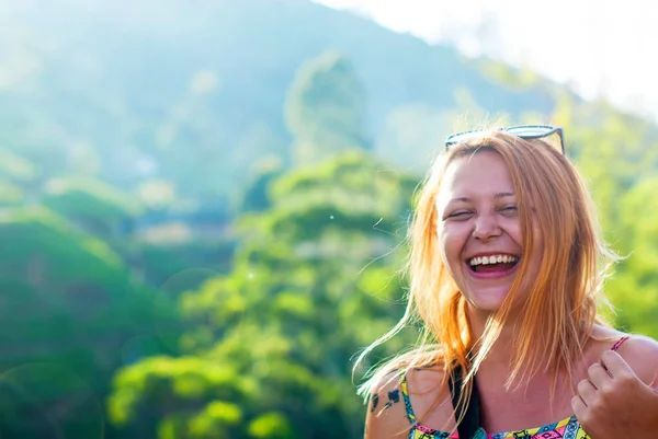 Kızıl saçlı kızla güzel traş tapınaklar mutluluk dağlar arka planı ile gülüyor
