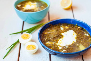 Derin tabak içinde yeşil pancar çorbası. Ispanak ve iki derin mavi tabak yumurta ile kuzukulağı çorbası.