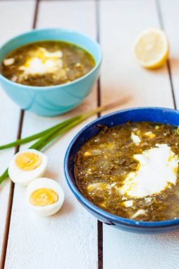 Derin tabak içinde yeşil pancar çorbası. Ispanak ve iki derin mavi tabak yumurta ile kuzukulağı çorbası.