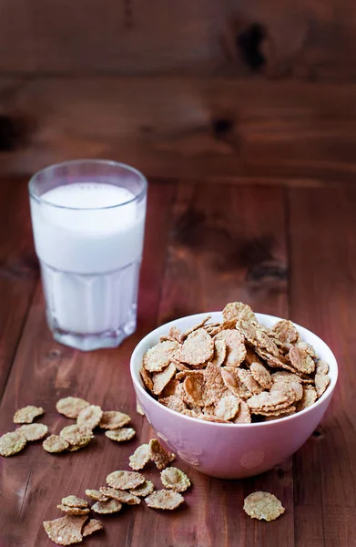 Flakes of cereals for breakfast with a glass of milk. Oat flakes in a deep bowl on a wooden table. Flakes with milk.
