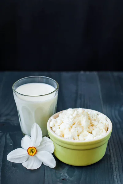 Cottage cheese and milk. Milk and granular cheese on a dark background. A glass of milk and a young cheese in a bowl.