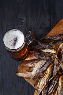 Bir bardak bira ile kurutulmuş balık. Deniz Bullhead Light bira. Kaya balığı ve bira karanlık bir arka plan üzerinde