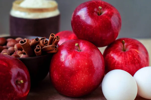 Rote Äpfel für einen Weihnachtskuchen mit Nussmehl und Eiern in Zimt-Fichtenzweigen. — Stockfoto