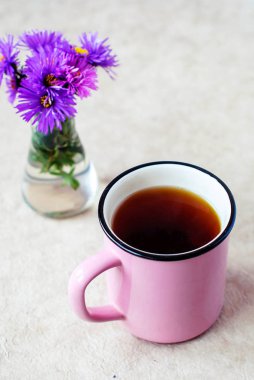 Siyah çay hafif bir arka plan ve mor çiçekler pembe bir fincan.